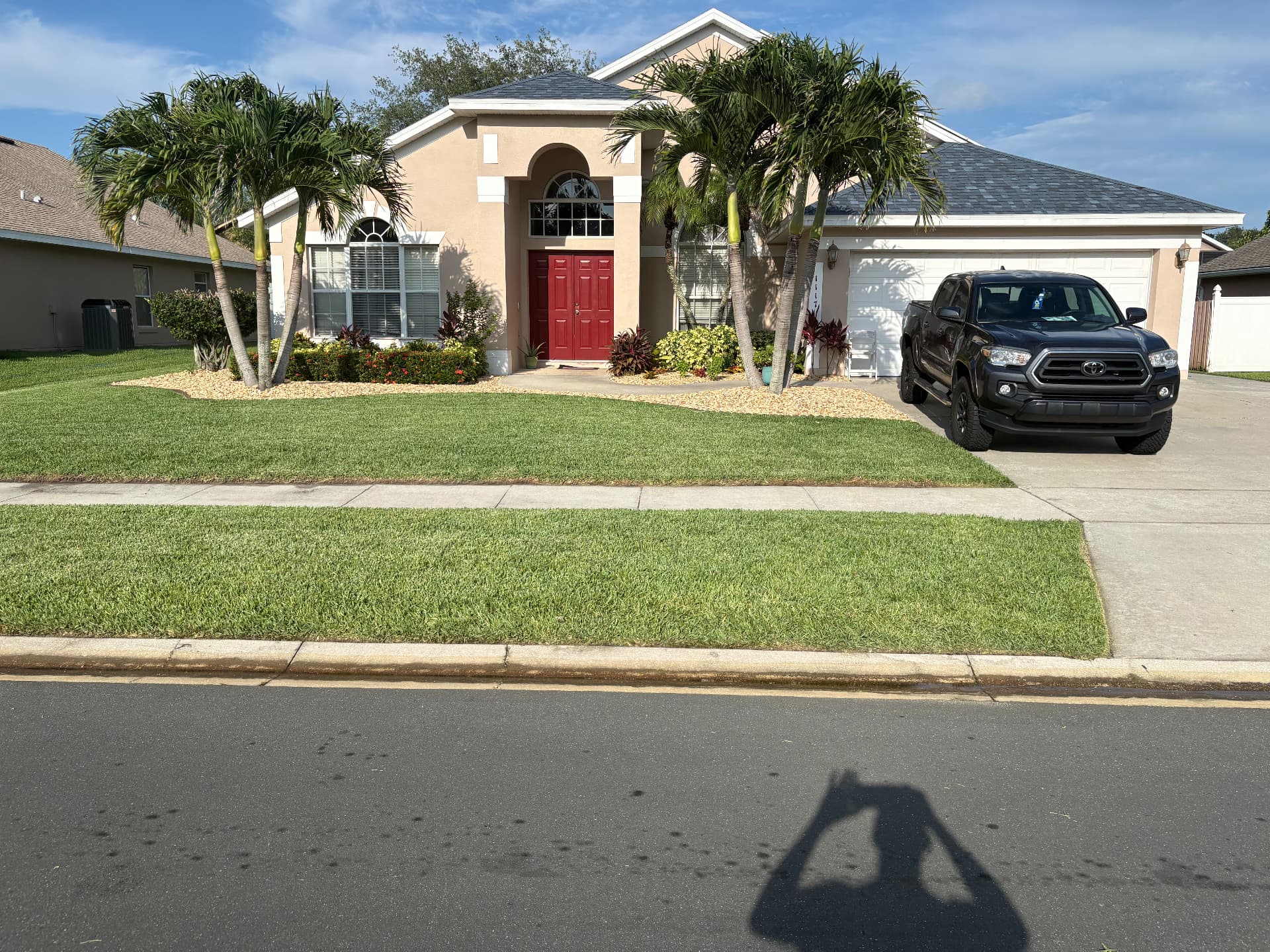 Manicured Florida home with palms, flower beds, and green lawn